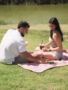 בנחל עגלת קפה אשדוד תמונה של זוג יושב לפיקניק על דשא ליד נחל